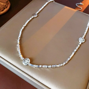 Detailed close-up of silver beaded necklace featuring three smiling face charms on display