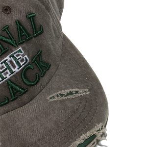 Close-up of vintage distressed baseball cap with 3D letter embroidery and frayed holes