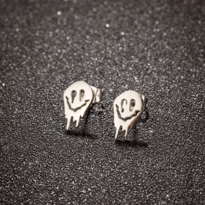 Dettaglio degli orecchini a lobo smiley in acciaio inossidabile argento su sfondo nero glitter