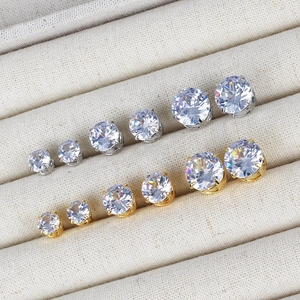 Classic silver and gold claw-set zircon earrings in various sizes on a beige jewelry tray