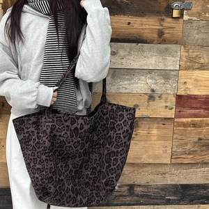 Close-up of leopard print tote bag with outer pocket and shoulder strap detail