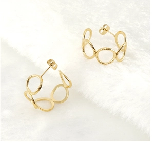 Macro view of textured 18K gold C-shaped stainless steel earrings on soft white plush