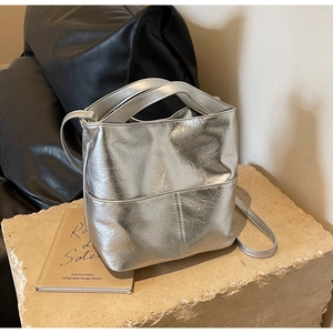 Detail of silver metallic bucket bag with pleated texture and adjustable shoulder strap