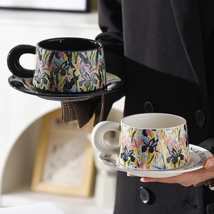 Ceramic coffee cup and saucer set featuring colorful iris flower designs on black and white