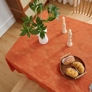 Detail shot of orange jacquard tablecloth fabric texture with embossed floral pattern