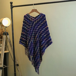 Gros plan d'un poncho tricoté bleu avec motifs ondulés colorés et détails à franges