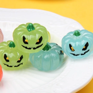 Detailed view of glow-in-the-dark resin pumpkin charms on a white embossed plate