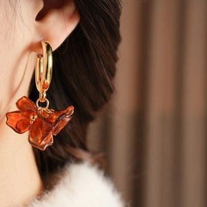 Close-up of vintage C-shaped amber resin flower petal earrings on model's ear