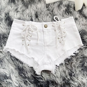 Dettaglio degli shorts in denim bianco con lacci laterali e orlo a frange rifinito