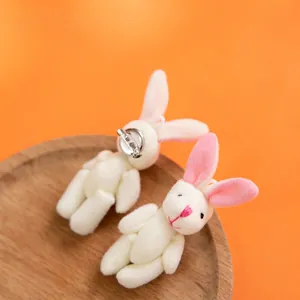 Coppia di spille a forma di coniglio in peluche su vassoio in legno e sfondo arancione