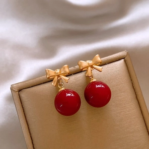 Detail of red bow earrings with high-gloss beads on elegant gold jewelry display box