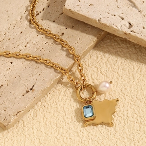 Macro shot of 18K gold plated necklace with blue gemstone and pearl on stone