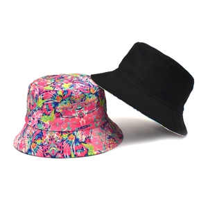 Flat lay of double-sided bucket hats featuring colorful floral print and solid black canvas