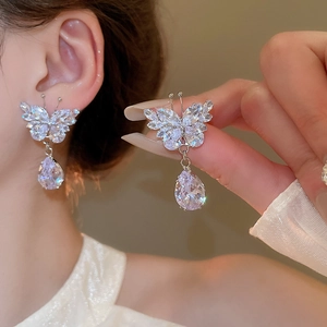 Close-up of silver butterfly earrings with zircon teardrop tassels on model