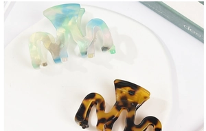 Close-up of wavy iridescent and tortoise shell acetate hair claws on a white tray