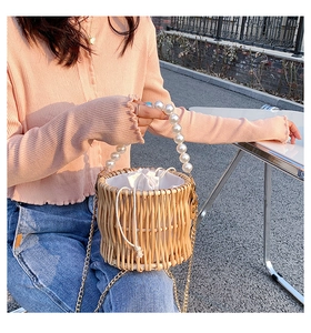 Detail showing the straw woven bucket bag with pearl handle and golden chain strap