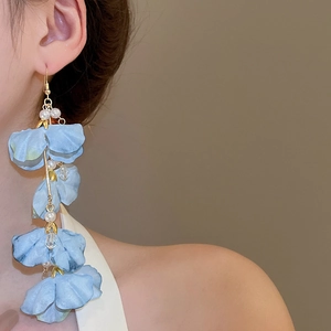 Détail de boucles d'oreilles fleurs en tissu bleu clair avec perles sur mannequin