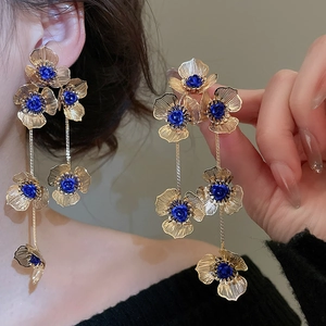 Detailed macro view of large gold tassel flower earrings with blue rose center details