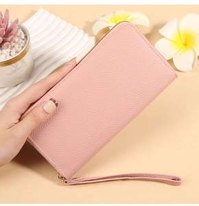 Pink lychee texture long wallet with gold zipper and wristlet held in hand for detail