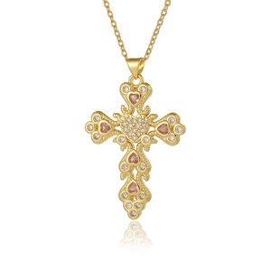 Detail shot of a gold cross pendant with pink and clear zircon stones on a white background