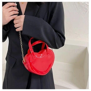 Detail of red heart jelly bag with gold chain strap on a black blazer background