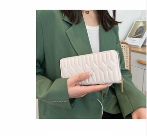 Elegant white quilted long wallet held by model in professional suit, zipper design