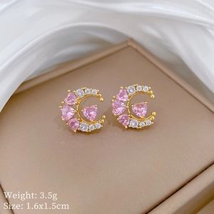 Detailed view of golden moon earrings with pink heart stones and white zircon details