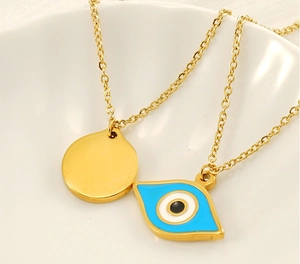Detailed view of a gold-plated evil eye necklace with blue enamel pendant in a white bowl