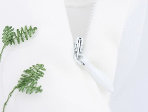 Gros plan sur la fermeture éclair invisible et la broderie de plante sur tulle blanc