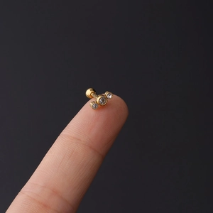 Close-up of 16g stainless steel helix stud with three curved zircons on a fingertip