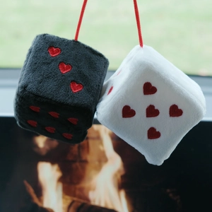 Detail of plush car dice hanger in black and white with red heart embroidery on the surface