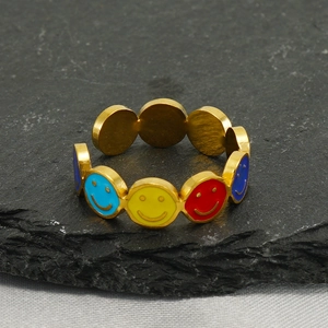 Détail de bagues ajustables en émail avec smileys colorés sur fond de pierre naturelle