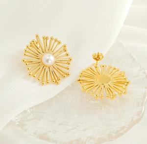 Detail of gold sunflower stud earrings with a central pearl on a white silk background