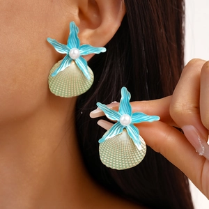 Close-up of ocean-style starfish and seashell earrings with pearls on ear