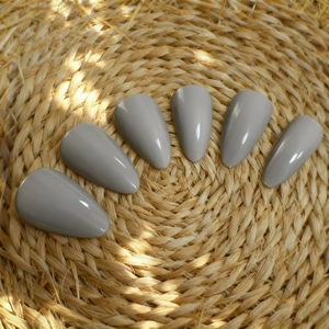 Glossy Morandi grey almond shape press-on nails set on a natural woven mat background