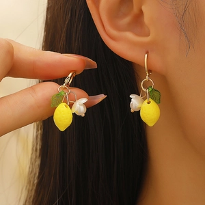 Detail of yellow lemon earrings with white flowers and green leaves on a model