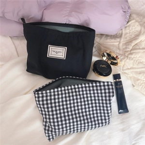 Detail of black and white checkered makeup bag set with a minimalist black zipper pouch