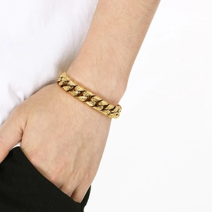 Gros plan d'un bracelet gourmette doré avec gravures paisley complexes sur le poignet