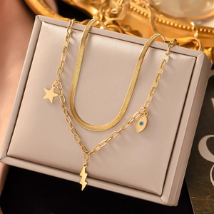 Detail of gold titanium double necklace with snake chain and blue evil eye charms