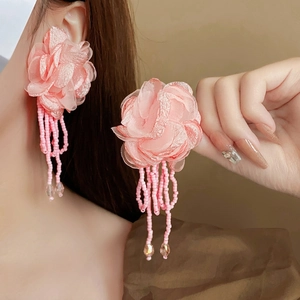 Elegant pink fabric flower earrings with beaded tassels shown worn on a model