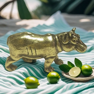 Solid brass hippo figurine statue with a metallic texture on a decorative fabric