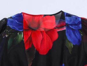 Detailed view of the crew neck and chiffon floral pattern on a black short sleeve top