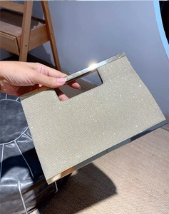 Detail of golden glitter evening clutch featuring ribbed texture and metallic frame handle