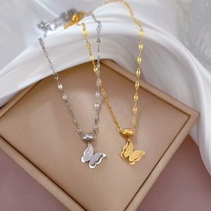Minimalist double-layered butterfly necklace set in gold and silver on a beige jewelry box