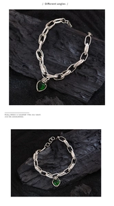 Detail view showing different angles of silver bracelet with green heart and cross charm