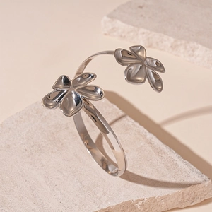 Gros plan détaillé du bracelet manchette fleur en métal argenté poli sur pierre crème