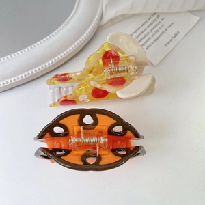 Close-up of a pizza-shaped hair claw and oval hair clip made of premium acetate