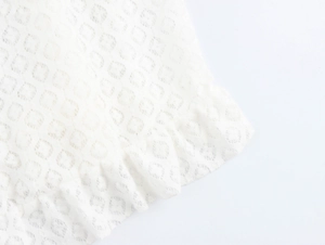 Detail of white lace dress showing circular hollow texture and pleated edge craftsmanship
