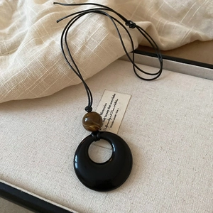 Detail of vintage necklace with a black circular pendant and a textured brown bead