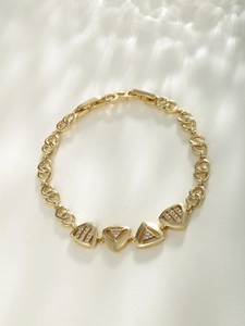 Detailed close-up of golden geometric triangle bracelet with sparkling zircon inlays